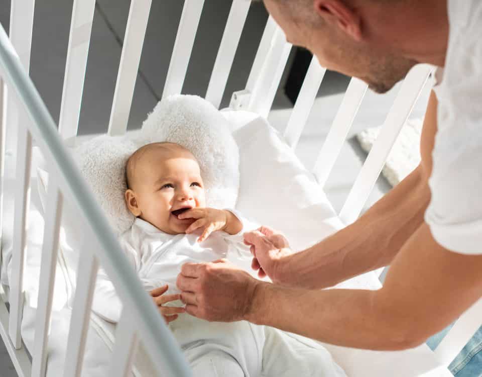 Grinsendes Baby liegt im Bettchen